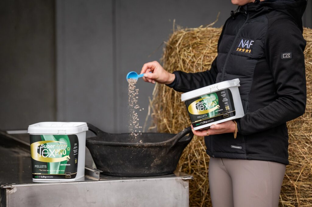 Reiterin gibt NAF Superflex PRO Omega zu Kraftfutterration